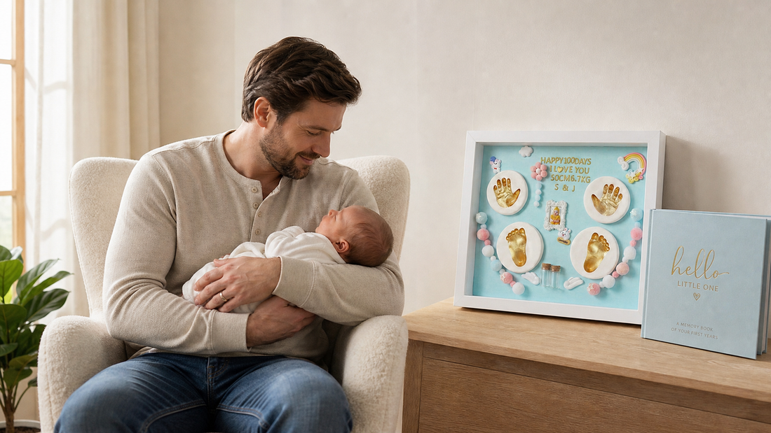 Father cradling newborn baby in nursery chair with inkless handprint keepsake frame and memory book on side table