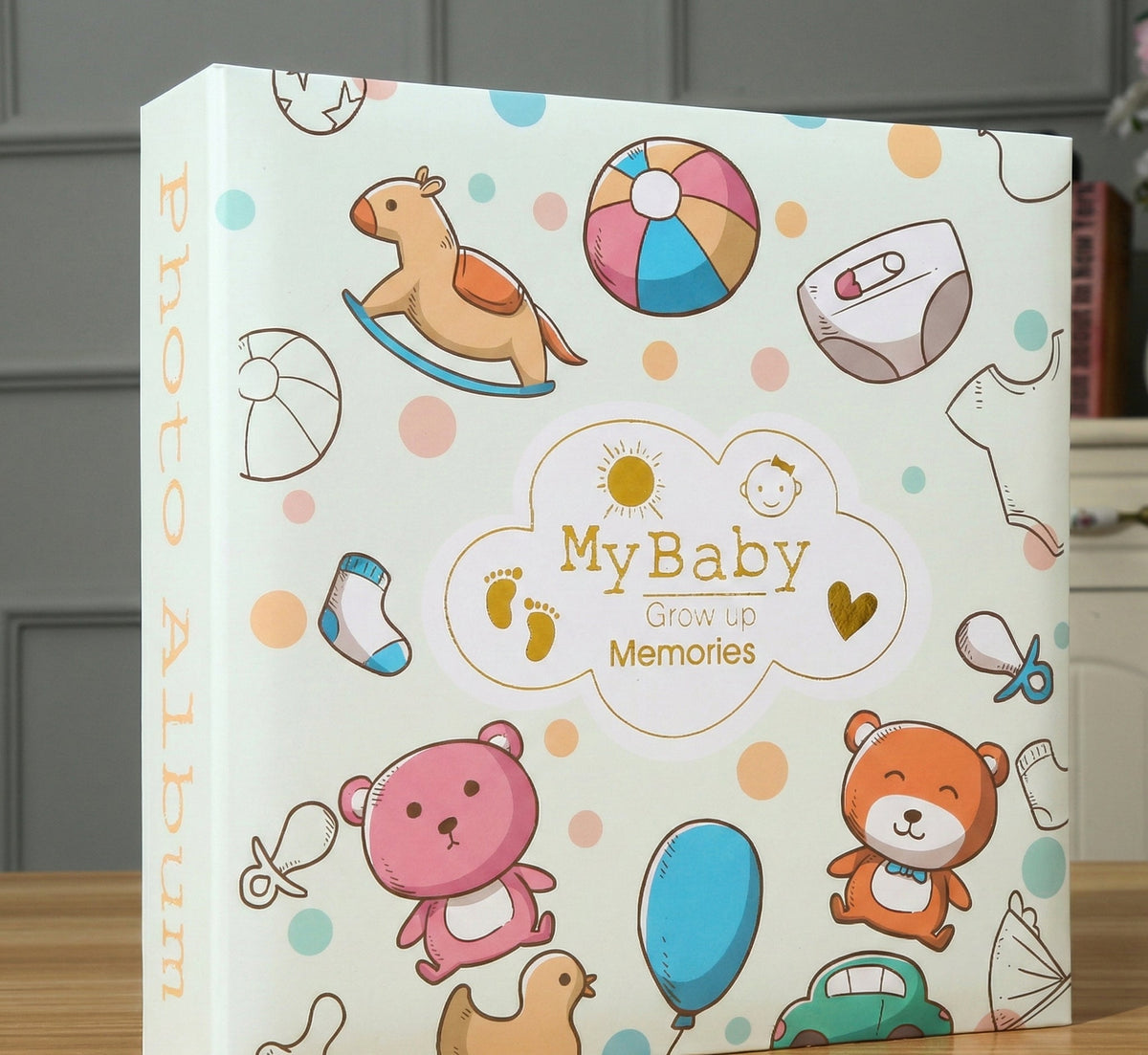 Kiddospot hardbound baby memory book open on wooden table with pen and photos