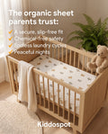 "Kiddospot's organic cotton fitted sheet on a crib with a toy and swaddle hanging on sides."
