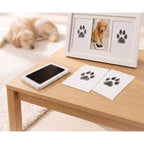 Inkless pet paw print pad and dog paw print cards on oak table with premium wooden frame included in kit