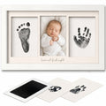 "A white three-frame baby keepsake photo frame displayed with sample prints and two sample fingerprint cards below. The center frame shows a sleeping newborn baby in a white outfit, while the side frames display black baby footprints and handprints on white backgrounds."