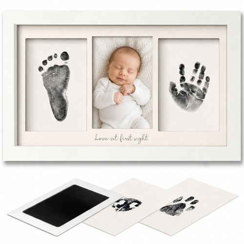 A white three-frame baby keepsake photo frame displayed with sample prints and two sample fingerprint cards below. The center frame shows a sleeping newborn baby in a white outfit, while the side frames display black baby footprints and handprints on white backgrounds.