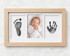 Newborn inkless print kit with natural wood frame, showing handprint and footprint impression cards on a white background