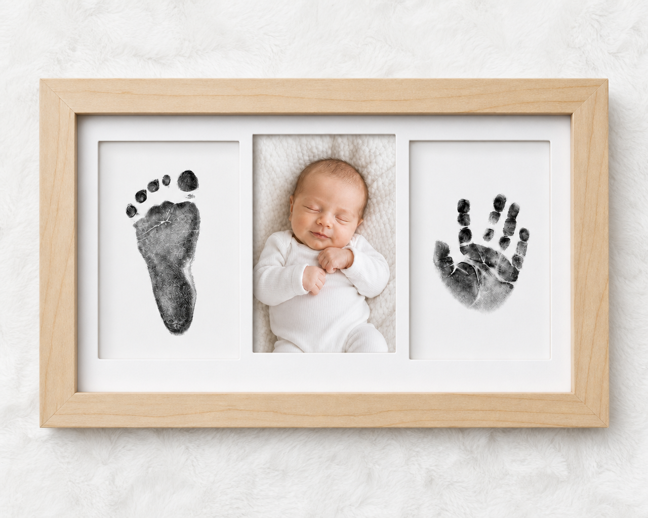 Newborn inkless print kit with natural wood frame, showing handprint and footprint impression cards on a white background