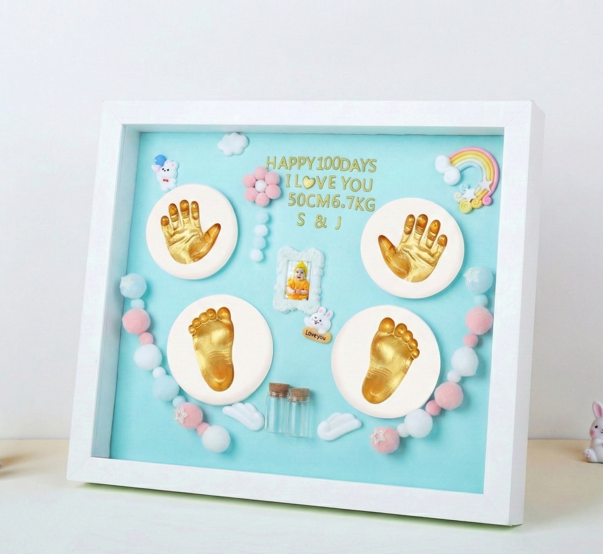 Baby milestone shadow box with hand and footprints on a light blue background