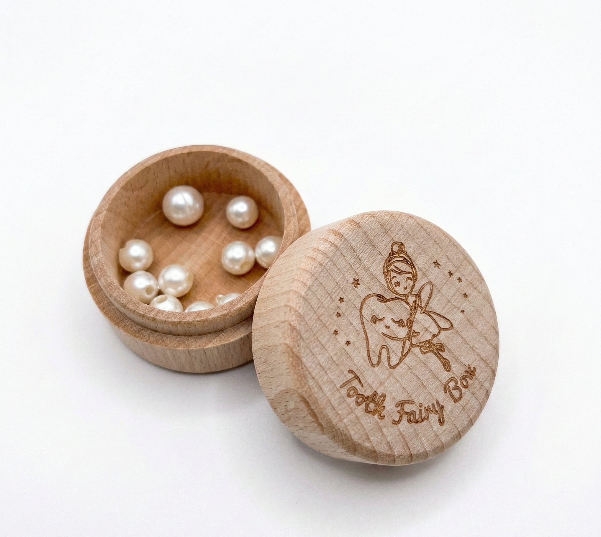 Wooden box with 'Tooth Fairy Box' lid containing small pearls on a white background