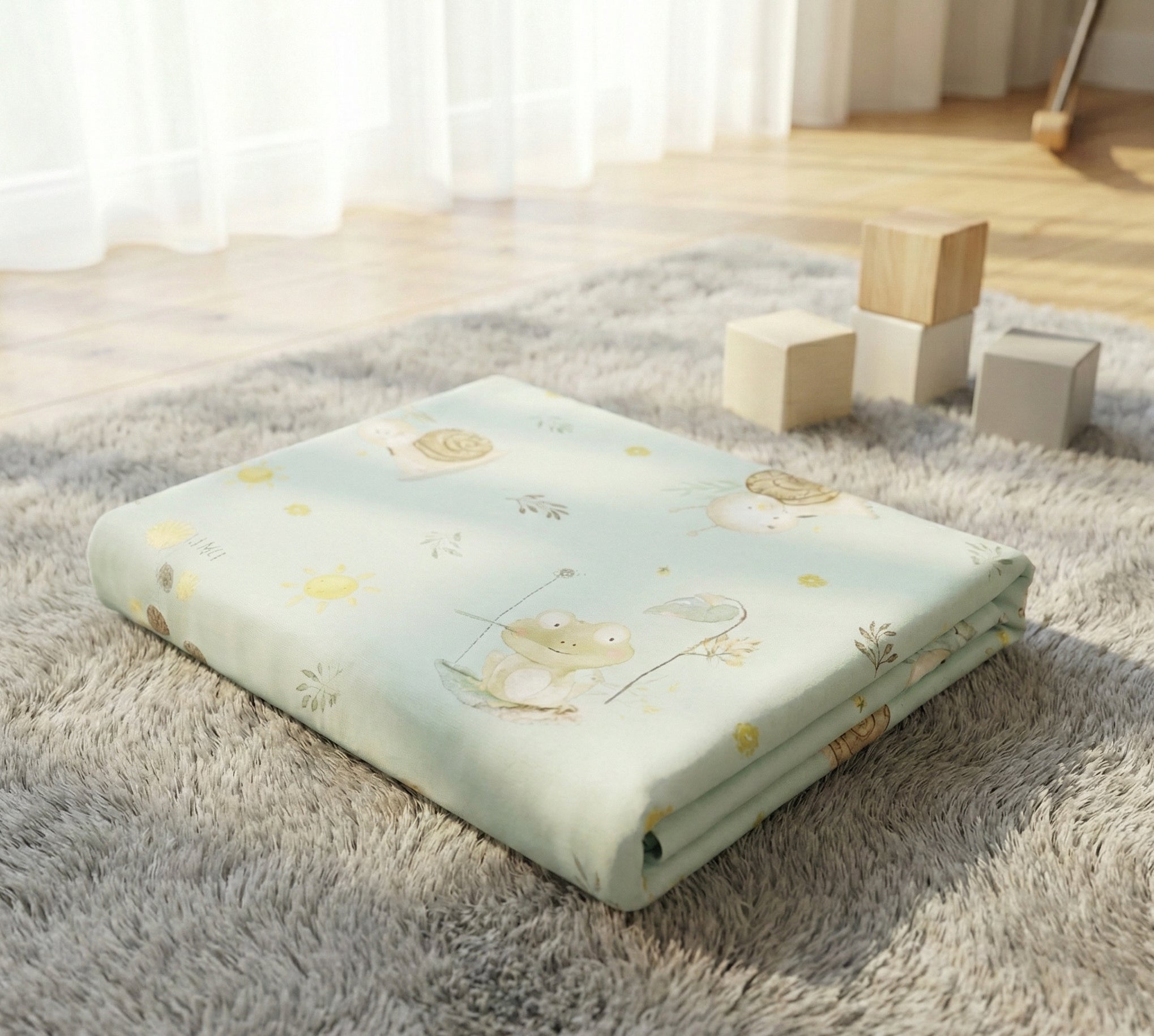 Folded crib mattress with frog design on a fluffy rug
