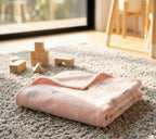 Pink blanket with star patterns on a carpeted floor with wooden blocks