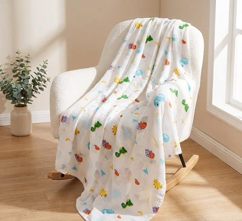 Kiddospot organic muslin swaddle dinosaur print draped over nursery chair — GOTS certified