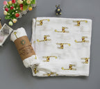 Baby blanket with giraffe pattern and wrapped product on a gray surface
