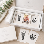 Baby hand and footprints in a 'little prints' box with a photo of a baby on a wooden surface.
