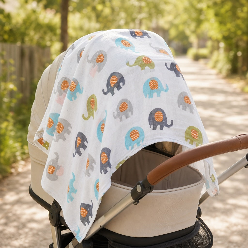 Kiddospot organic cotton muslin swaddle elephant print draped over a pram as a sun shade — showing the multi-use versatility of the 120x120cm GOTS certified swaddle wrap. Bright outdoor setting with natural light.