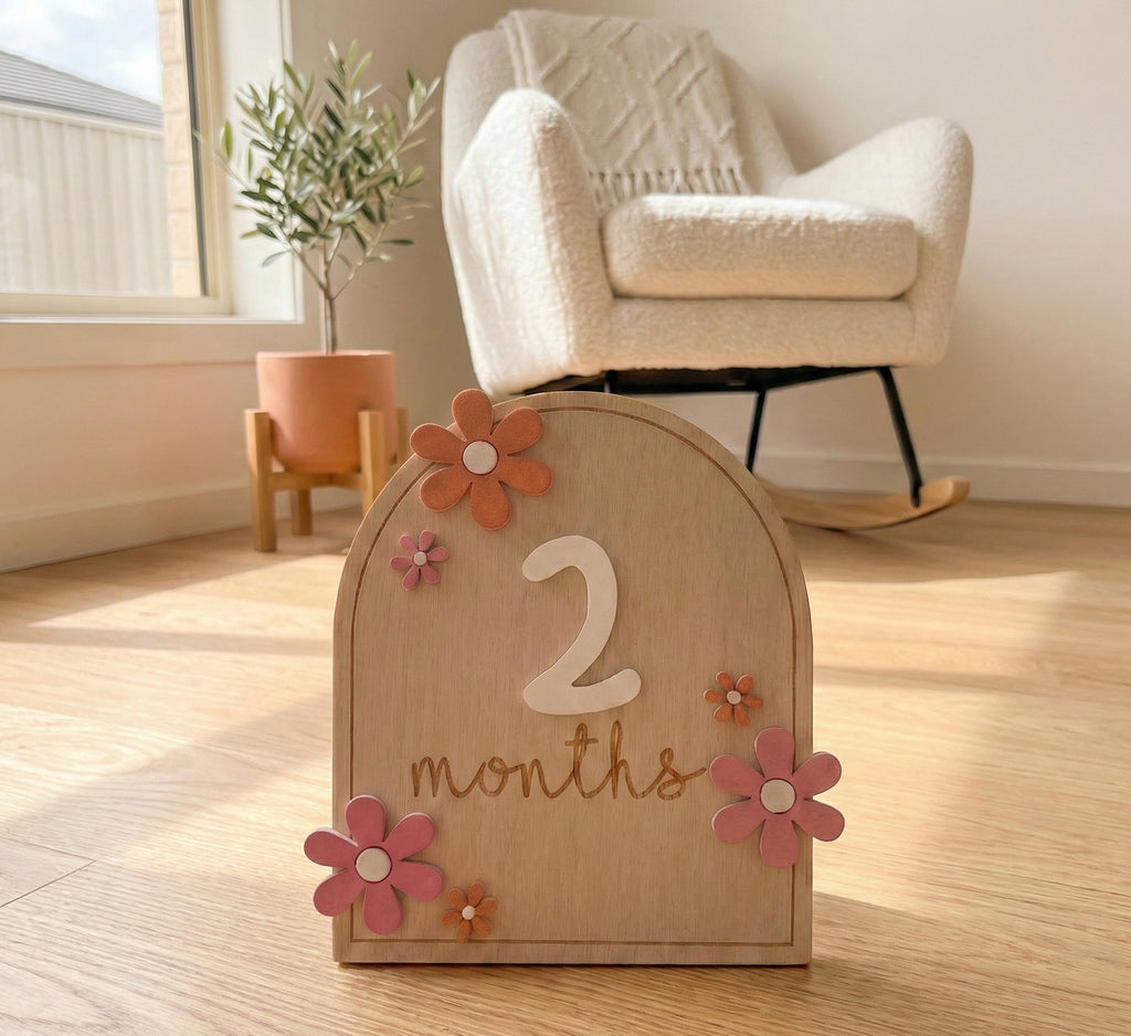Kiddospot wooden milestone card displaying 2 months on wooden floor — reusable baby prop