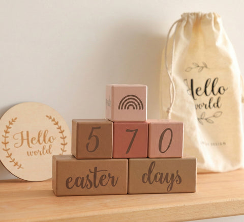 Kiddospot pink wooden baby milestone blocks stacked on wooden surface — baby photo prop