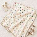 "Organic baby blanket heart design, GOTS-certified cotton knit, styled with cream booties and cotton bolls"