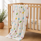 A Kiddospot white baby blanket with a colorful dinosaur and cloud pattern draped over a light wood crib in a bright nursery setting.