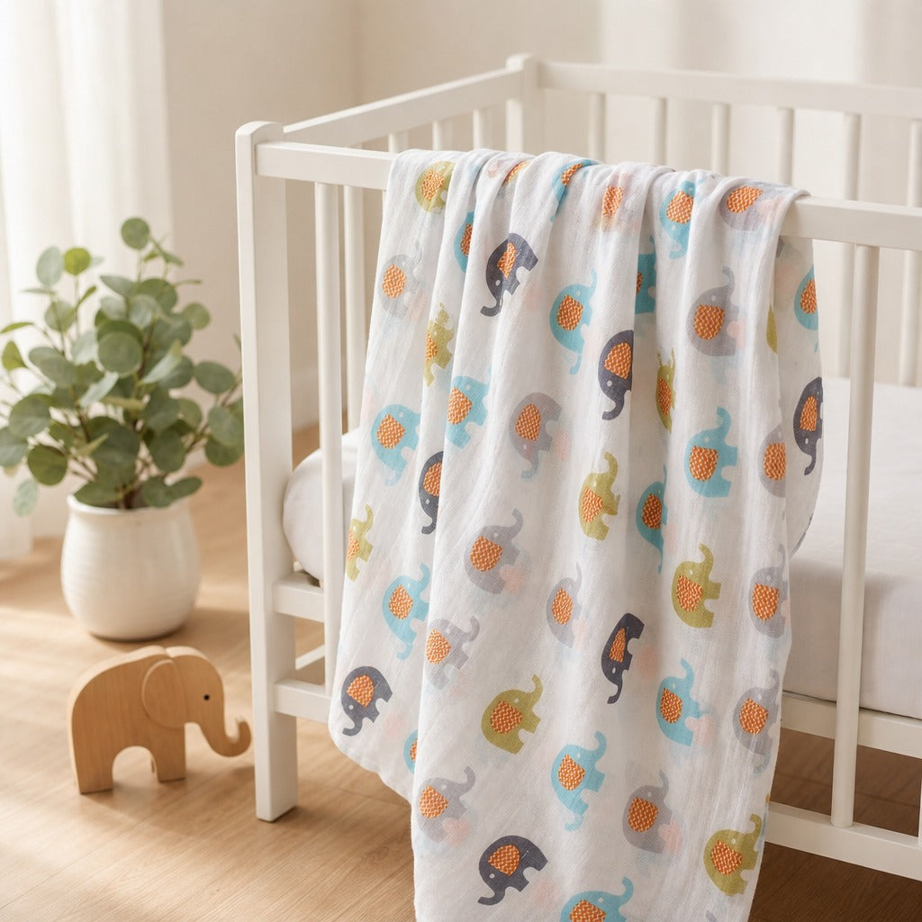 A Kiddospot white muslin baby blanket with a colorful elephant print draped over a white wooden crib in a bright nursery setting.