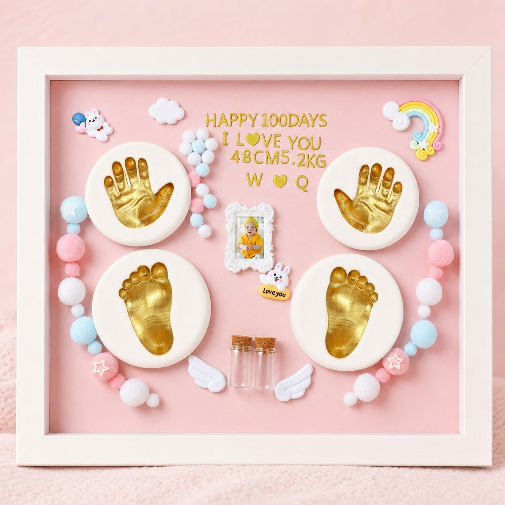 Kiddospot framed 100-day baby milestone shadow box display on a pink background. The white frame contains gold baby handprints and footprints on round white plaques, a small photo frame, pastel beads, white angel wings, and gold text reading 'HAPPY 100 DAYS I LOVE YOU 48CM5.