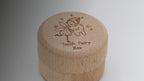 Kiddospot Wooden Tooth Fairy Box Classic — small cylindrical solid beechwood screw-top box approximately 38–45mm diameter with a laser-engraved whimsical tooth fairy illustration hugging a smiling tooth, surrounded by twinkling stars, and "Tooth Fairy Box" in cursive script on the lid. Natural matte finish. Roomy interior holds all 20 baby teeth. Childhood keepsake for ages 5 and up. Not a toy — a meaningful gift from parents, grandparents and gift givers. Free AU shipping. kiddospot.com