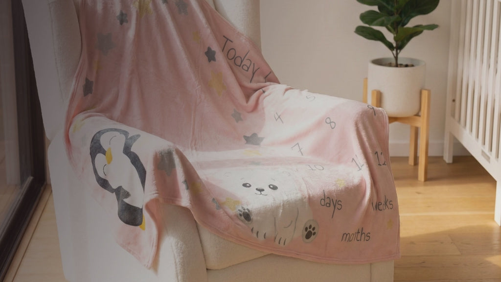 Kiddospot Pink Baby Milestone Blanket — soft blush pink base with kawaii polar bear, penguin, scattered shimmering gold and charcoal grey stars, and "Today I am" milestone tracking text for Weeks 1–4 and Months 1–12. 100x150cm ultra-soft high-pile flannel fleece. Perfect monthly baby photo prop and baby shower gift. Free AU shipping. kiddospot.com