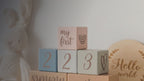 Kiddospot Blue Wooden Baby Milestone Blocks — set of 6 matte-painted solid wood blocks in muted boho tones of dusty rose, powder blue, sage green, stone grey and warm tan. Dark brown handwritten-style cursive text tracks months, weeks, days and special occasions including firsts and milestones. Perfect monthly baby photo prop and baby shower gift. Free AU shipping. kiddospot.com