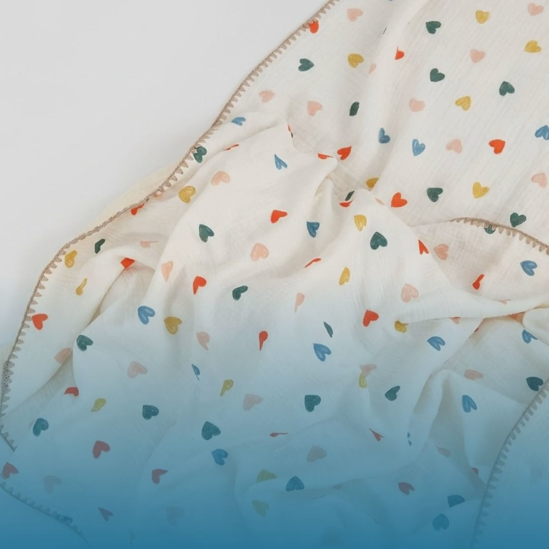 Kiddospot GOTS-certified organic cotton baby blanket in a scattered heart design, made from lightweight breathable muslin double-gauze measuring 120 x 150cm. 100% chemical-free from field to finished product, safe for newborn skin. Ideal baby shower gift. Free AU shipping. kiddospot.com.