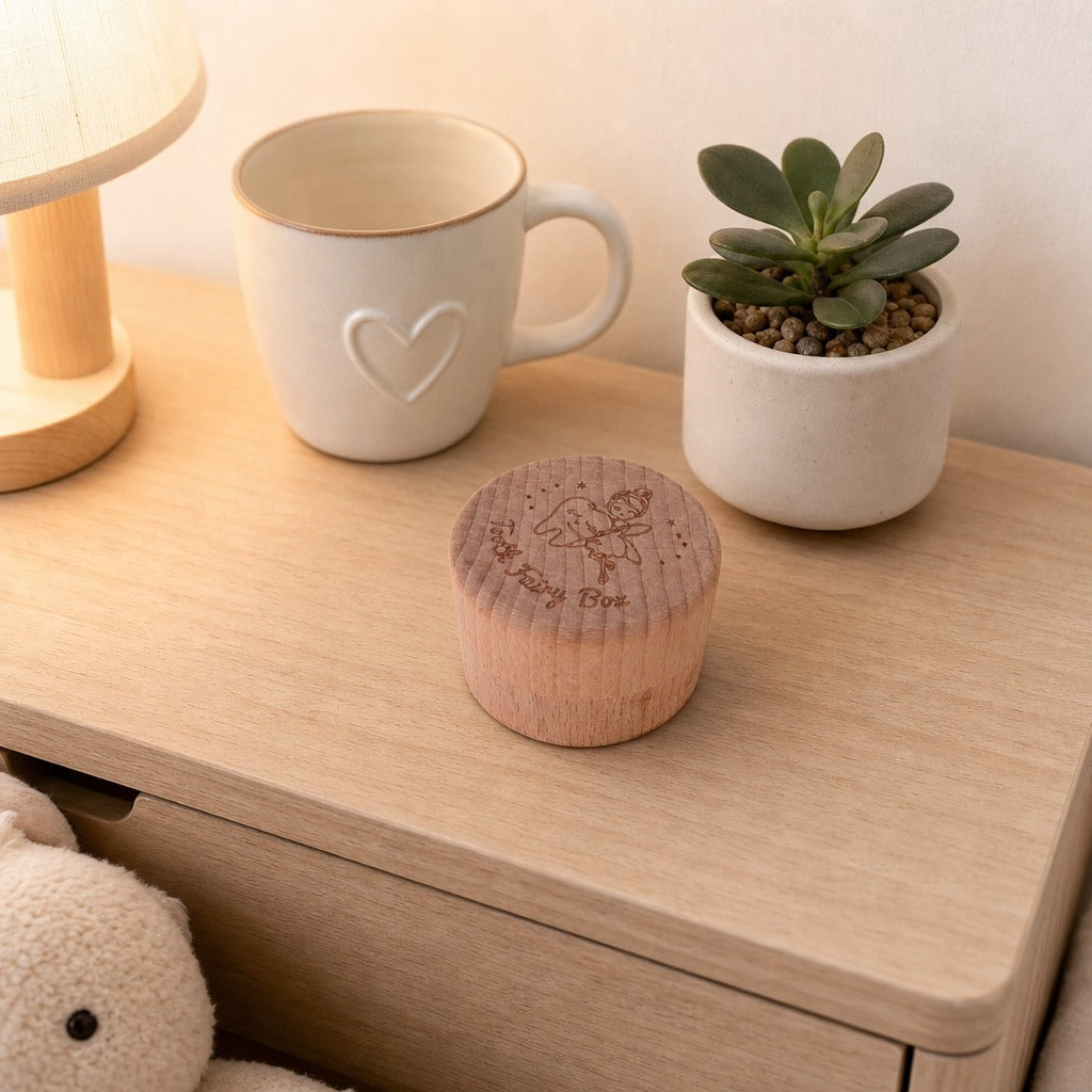 Kiddospot small round wooden keepsake box with a floral engraving sits on a light wood bedside table, styled with a cream ceramic mug, a small potted succulent, and a plush toy.